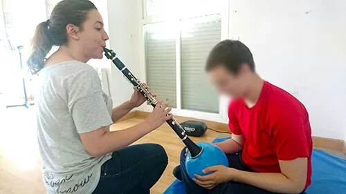 Monitora tocando el clarinete junto a un participante que sostiene un cuenco sonoro