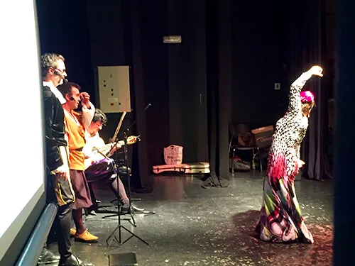 Bailaora de flamenco con vestido de lunares en escena, acompañada por músicos