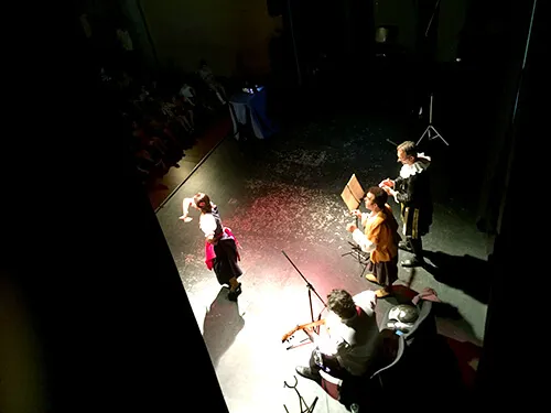 Escena teatral iluminada por un foco cenital sobre el escenario a oscuras