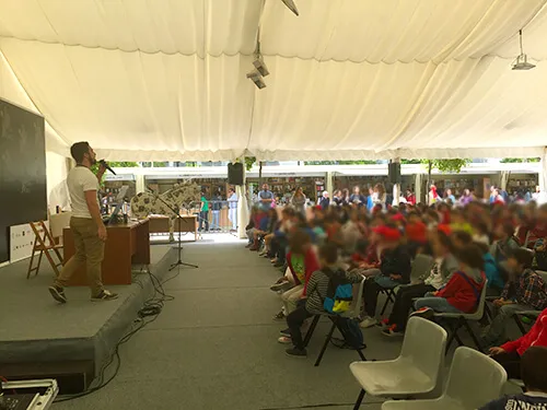 Público numeroso asistiendo a una actuación en la carpa de una feria del libro