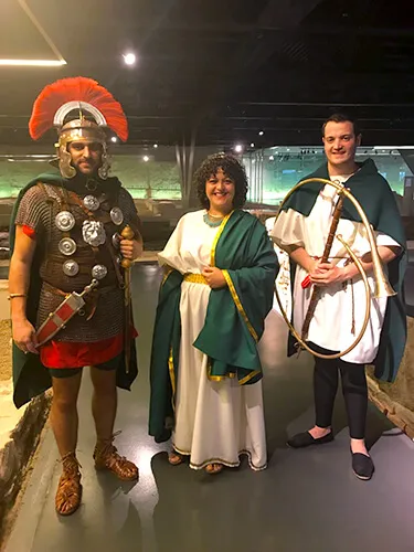 Grupo con indumentaria romana —un legionario y varias personas togadas— en la sala de un museo