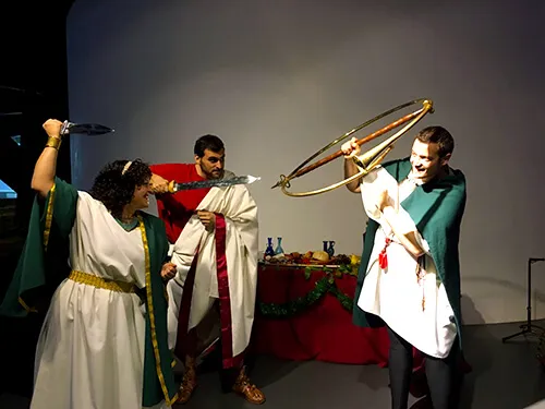 Recreación romana con arco y personajes togados en una escena didáctica