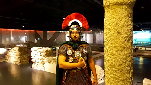 Recreador vestido de legionario romano junto a una columna en un museo