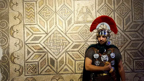 Recreador vestido de legionario romano ante un mosaico romano