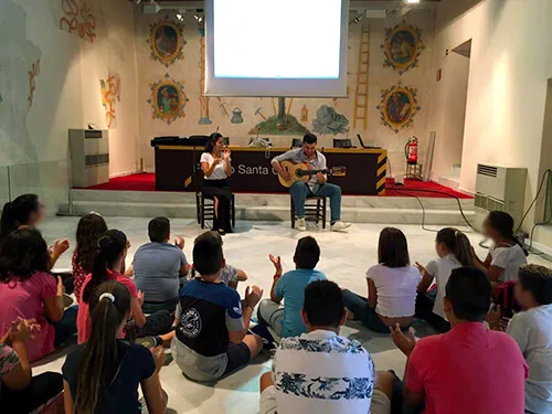 Charla didáctica con público infantil sentado en una sala con proyección