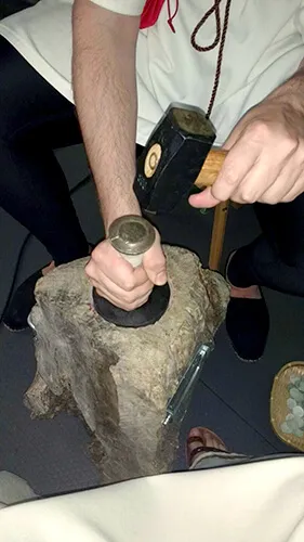 Manos moliendo con un mortero de piedra en un taller de arqueología experimental