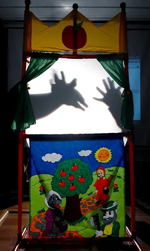 Teatro de sombras con decorado infantil y la silueta de unas manos proyectada